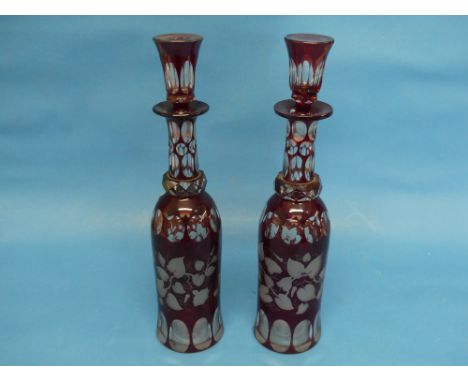 A pair of early 20thC Bohemian ruby flash Decanters, bottle shape, one with chipped stopper, 13½in (34cm) high to top of stop