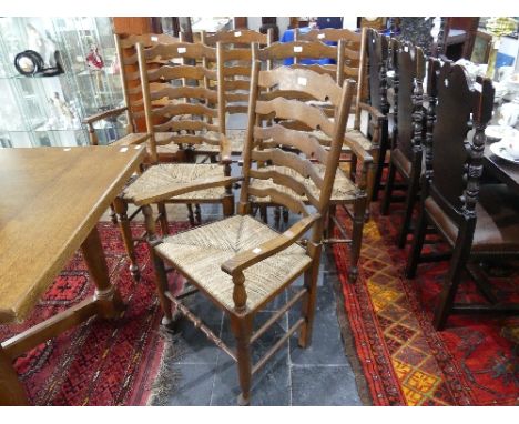 A set of six oak ladder-back dining elbow chairs, with shaped splats, rush seats and turned legs joined by stretchers, 43in (