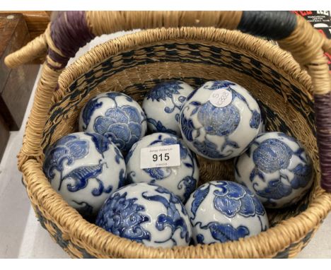 A QUANTITY OF CERAMIC BLUE AND WHITE ORNAMENTAL BALLS IN A VINTAGE BASKET 
