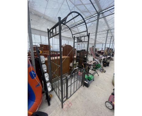 A LARGE DECORATIVE METAL ARCHWAY WITH PEDESTRIAN GATE 