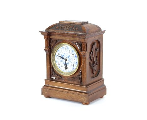 A later 19th Century carved oak single hole mantel clock with blue and white enamel dial