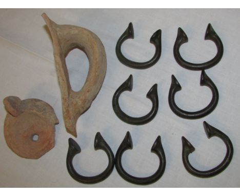Seven bronze torcs / slave manillas (each about 6cm diameter), a pottery handle fragment, and a terracotta oil lamp fragment 