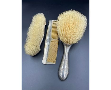 A three silver backed piece dressing table set to include two brushes and a comb.