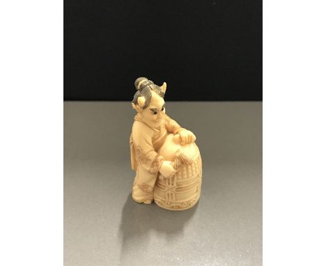 SUPERB QUALITY SIGNED JAPANESE IVORY NETSUKE, a study of a young Geisha wearing a devil's head mask as she beats a decorated 