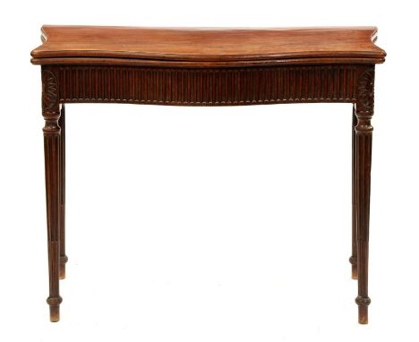 A George III serpentine mahogany tea table, with nulled frieze, on stop fluted tapering turned legs headed by carved oval pat