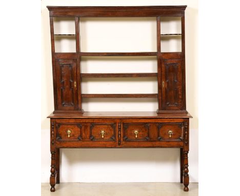An oak dresser, early 20th c, the rack with two spice cupboards with geometrically panelled doors, the base with conforming d