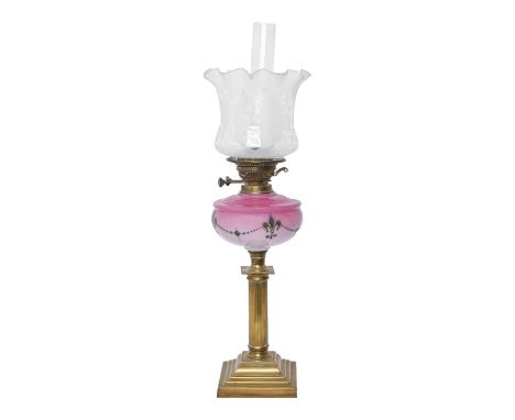 A brass columnar oil lamp, c1900, the shaded pink glass font decorated in green with fleur de lis, brass burner, etched shade