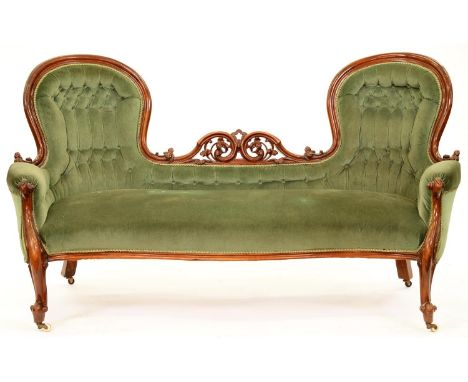 A Victorian carved serpentine walnut sofa, with twin arched chair backs divided by pierced and scrolling foliage, pottery cas