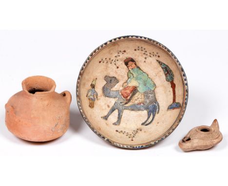 A Persian earthenware bowl, the painted and glazed interior with a figure on a camel, 17cm diam, a Roman pottery oil lamp and