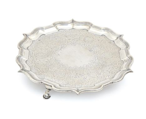 A Victorian silver salver, the field engraved with flowers and C-scrolls within bath border, on three feet, 27cm diam, by Haw