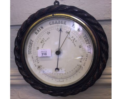 A wall mounted oak cased barometer with a rope twist detail to the rim, manufactured by Reaumur with thermometer with thick b