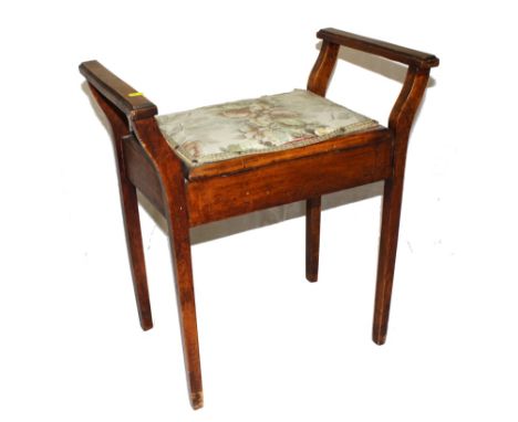 An Edwardian walnut piano stool with twin handle supports, upholstered lift up seat, raised on square tapering legs, 60cm wid