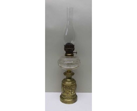 A Victorian oil lamp 42cm high, with glass funnel, 66cm, brass base with frieze of raised classical head profiles and leaves,
