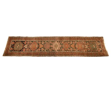 An Eastern hand woven carpet runner, of blue and russet ground in Kazak style.  308 x 88 cm.