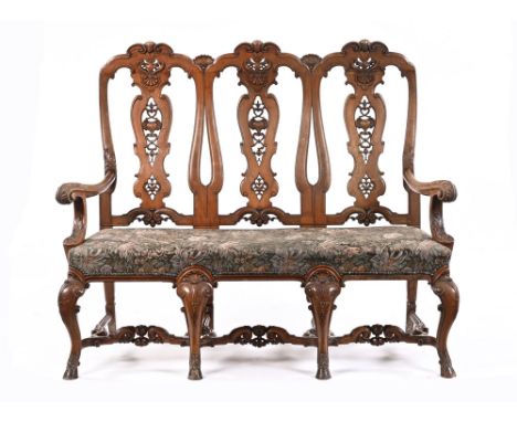 An early 20th century walnut framed triple chair back sofa, with extensive scroll vase and foliate splat backs, with sweep ac