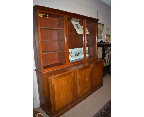 An early 20th Century mahogany cabinet, the three glazed doors enclosing shelves above base fitted three solid panel doors, 1