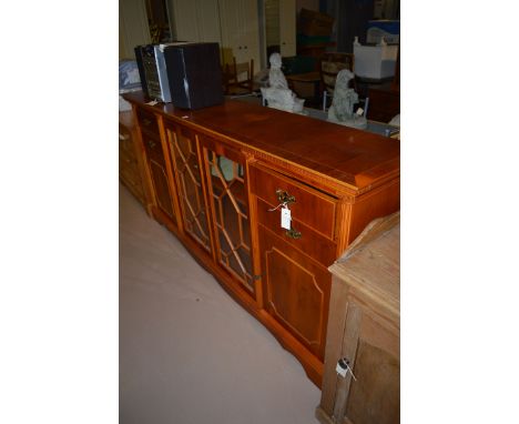 A reproduction yew wood display cabinet, the glazed astragal doors flanked by drawers and solid panel doors.