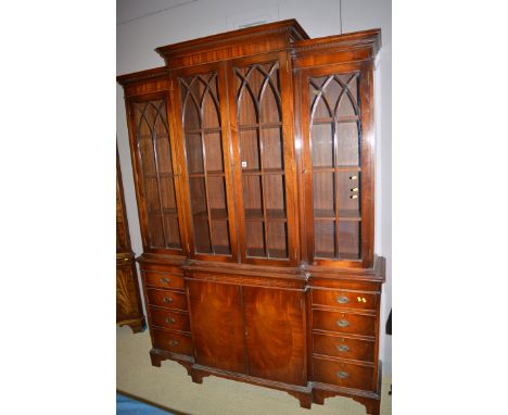 A reproduction mahogany breakfront display cabinet, by Wade, the glazed panel doors enclosing shelves above central slide and