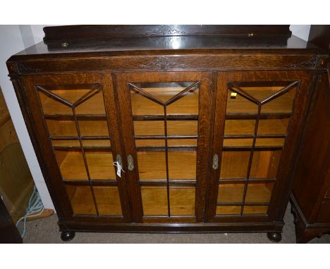 An early 20th Century oak display cabinet, fitted three glazed panel doors, 133cm wide.