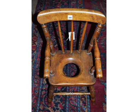 A Windsor style child's commode chair, with spindle back, turned arms and legs, the elm seat with a cut hole, 54cms high.