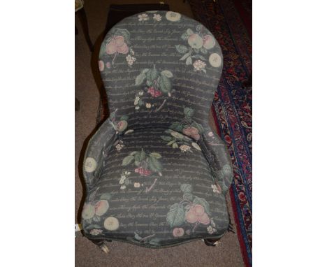 An early 20th Century nursing chair, the back arms and seat upholstered in fruit pattern material, raised on turned legs term