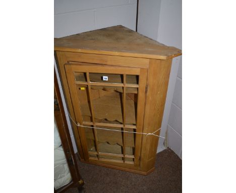 A stripped pine hanging corner cabinet, the glazed panel door enclosing shelves, 102cm high.