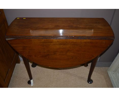 A George III mahogany drop-leaf table, the oval top with carved edge raised on turned tapering legs with gate action, termina