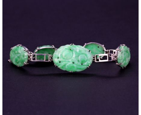 A white metal bracelet set with carved jade, L. 19cm.