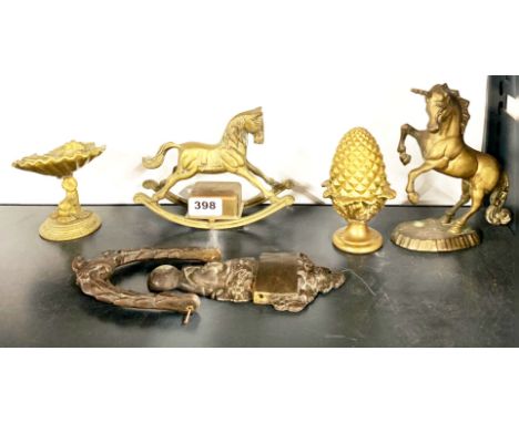 A brass door knocker and a group of other brass items, including a musical rocking horse.