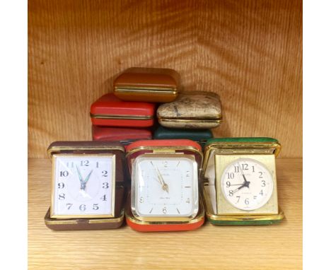 A group of ten vintage travel alarm clocks.