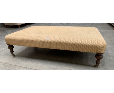 An upholstered stool on baluster turned legs with brass caps and castors. 36' x 60