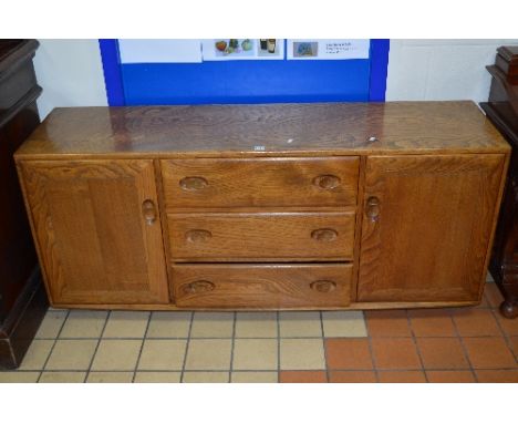 AN ERCOL ELM SIDEBOARD, with three central drawers on casters