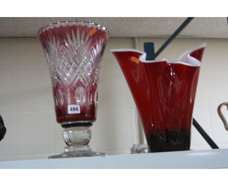 A LARGE RUBY FLASHED CUT GLASS FOOTED VASE, height approximately 35cm, together with another red glass handkerchief shape vas