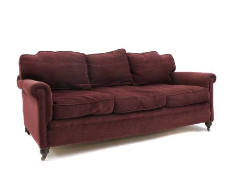 A late Victorian country house sofa,with deep red upholstery, raised on short turned supports terminating in brass castors,19