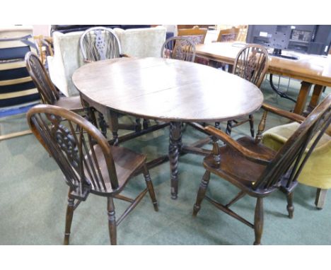 Oval shaped twin drop flap gate leg table in oak with six similar chairs