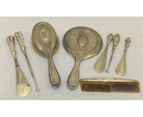 A silver backed hand mirror and matching brush, various silver handled shoe horns and button hooks and a silver mounted comb