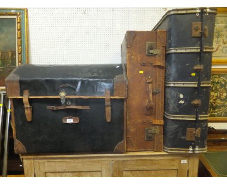 A black canvas covered dome topped trunk with leather corners, a brown leather trunk, a metal banded trunk, a stained wooden 