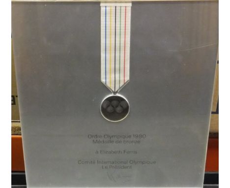 A 1980 Olympic medal awarded to Elizabeth Ferris, two framed and glazed Olympic Games posters, a framed and glazed reproducti