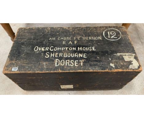 A 20th century black painted pine travelling chest with hinged lid, with two iron carrying handles, the top painted in white 