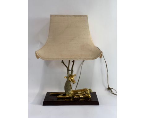 A mid-20th century lamp, the base modelled as a recumbent stylised deer on a dark stained oak plinth, with integral shade and