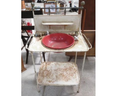 An early 20th Century painted metal washbasin unit the raised back with shelf and brass finials, the base with cut outs for t