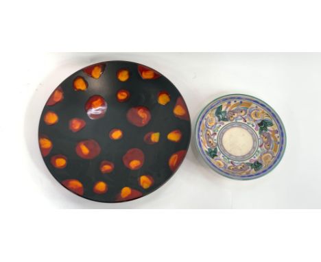 A large Poole pottery charger in a black matt glaze, decorated with red and orange blotches, 41cm diameter; together with a P