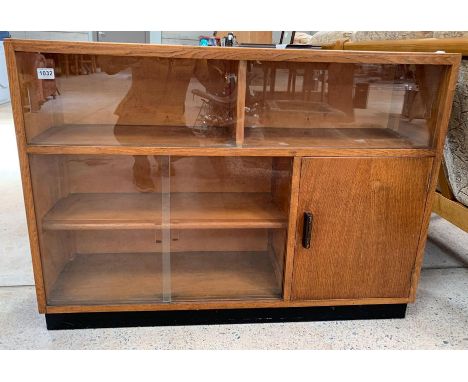 A mid-20th century oak unit, the top with divider and two sliding glass doors, below a compartment with fixed shelf and two s