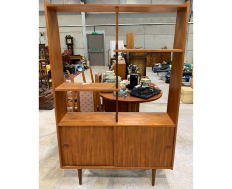 A mid-20th century teak display unit, of open shelf form with shaped supports , the base with two sliding doors with recessed