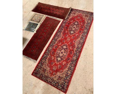 A small dark red wool runner, with repeating geometric borders and central repeating motifs, 131cm x 51cm; together with anot