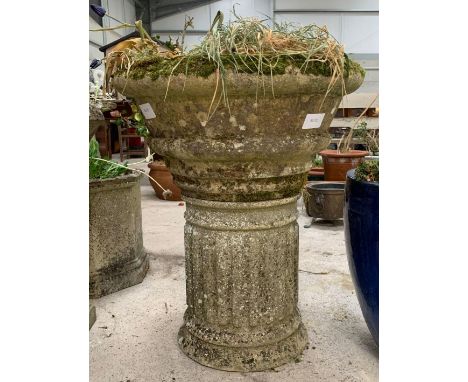 A circular reconstituted stone planter with ring moulded detail and a low fluted pillar, 60cms diam 72cms high. Viewing/colle