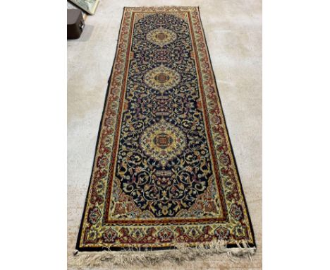A 20th century wool runner, of Persian design, with three central medallions within floral decoration and borders, on a dark 