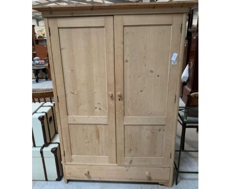 A stripped pine double wardrobe, the two panel doors opening to a long shelf and rail, with one long drawer to the base, 182c