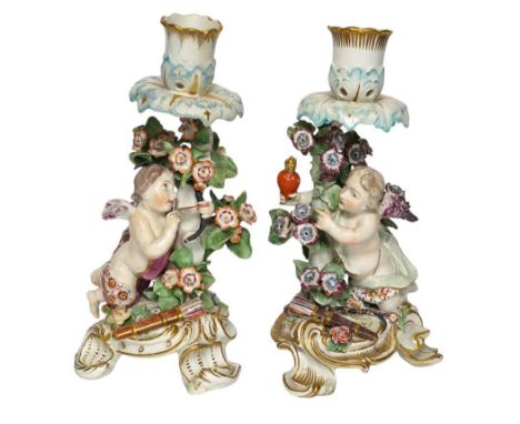 A pair of 19th century Derby porcelain candlesticks, with ‘winged cupid’ stems, 22cm. Condition - poor One candlestick has an