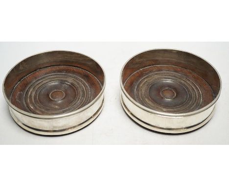 A pair of 19th century Continental white metal wine coasters, inset with turned mahogany bases, 12.5cm diameter. Condition - 